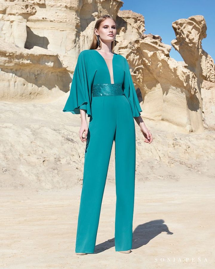 In questa foto una modella indossa una tuta elegante di Sonia Pena di colore verde acqua con scollo a V, maniche a tre quarti ampie e cinturone in vita con tessuto sparkling