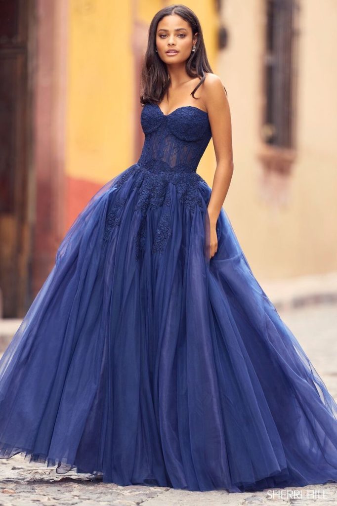 In questa foto una modella indossa un abito da cerimonia per testimone ampio di Sherri Hill di colore blu notte di tulle con scollo a cuore