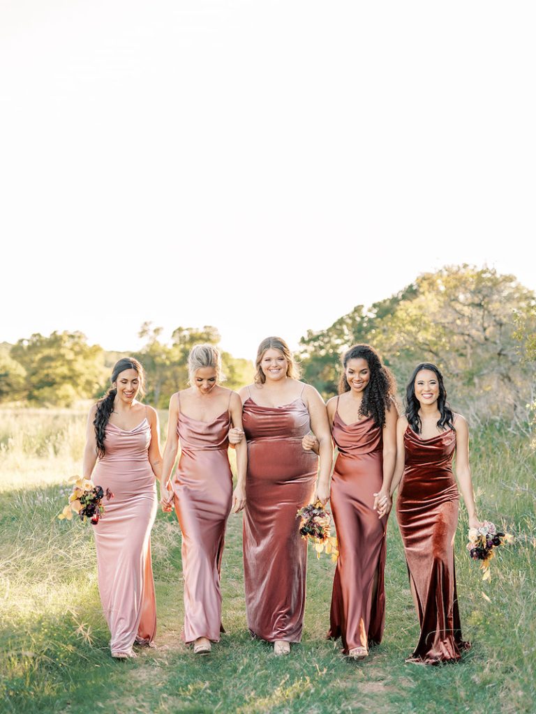 In questa foto cinque ragazze indossano abiti da cerimonia donna per damigelle lunghi di velluto in degradè nei toni del rosa antico