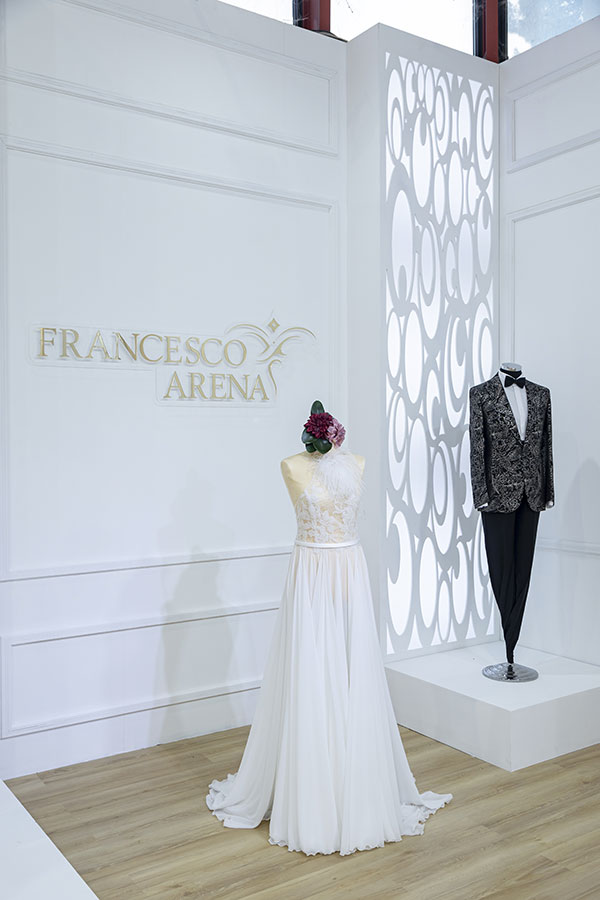 In questa foto un elegante abito da sposa scivolato ed un completo da sposa in esposizione dello stand dell'Atelier Francesco Arena al TuttiSposi 2022