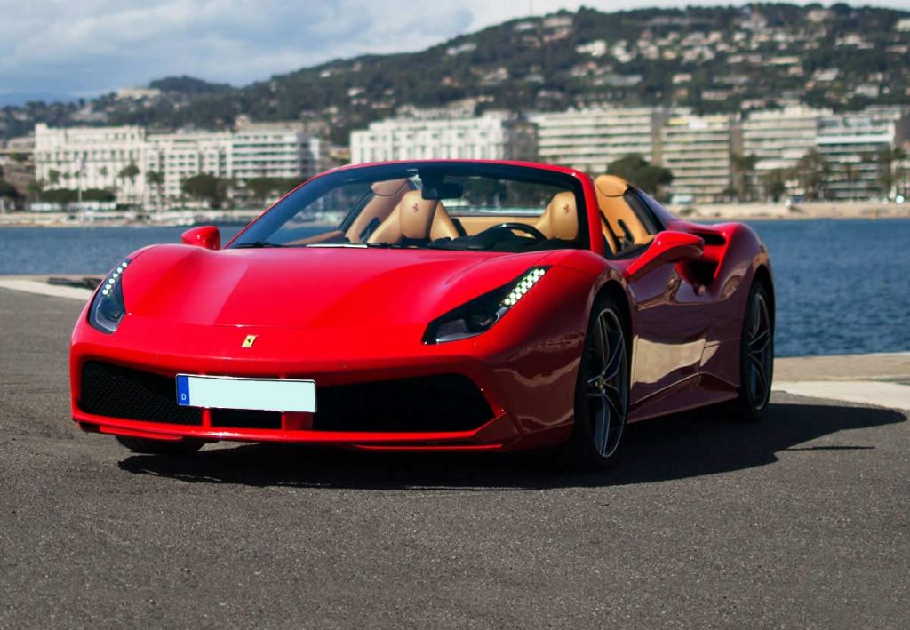 In questa foto una Ferrari di colore rosso per matrimonio ritratta su un porticciolo davanti al mare