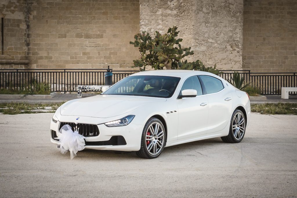 In questa foto una Maserati di colore bianco per matrimonio decorata con una coccarda di tulle di colore bianco