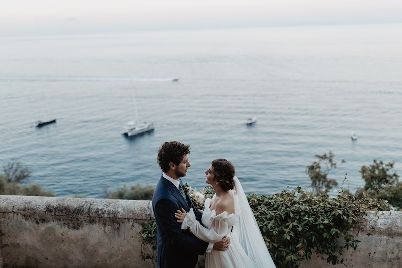 In questa foto due sposi si guardano abbracciati sullo sfondo del mare