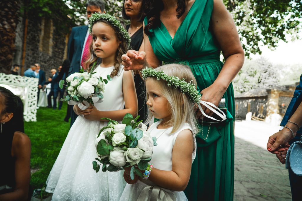 In questa foto le damigelle del matrimonio di Giuseppe e Giulia con vestitini bianchi, corona di fiori e bouquet bianco e verde