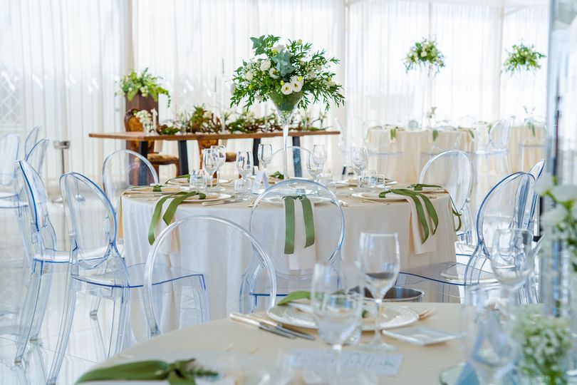 Un'elegante sala di Tenuta Amalthea. Raffinata mise en place con trasparenze, bianco e toni del verde 