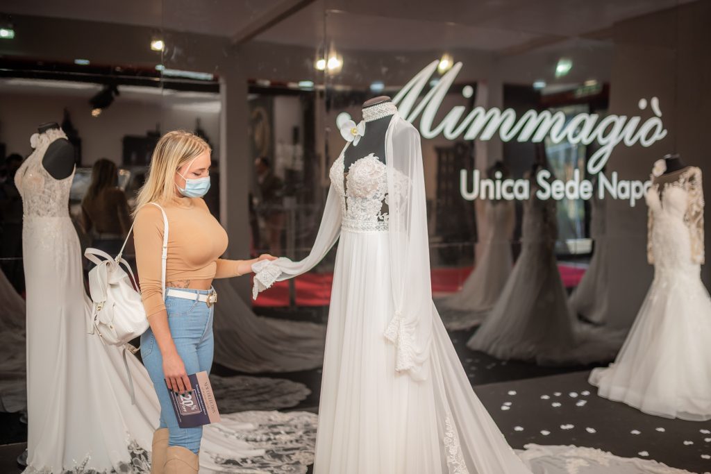 In questa foto una futura sposa ammira da vicino un abito esposto alla fiera Tutto Sposi 