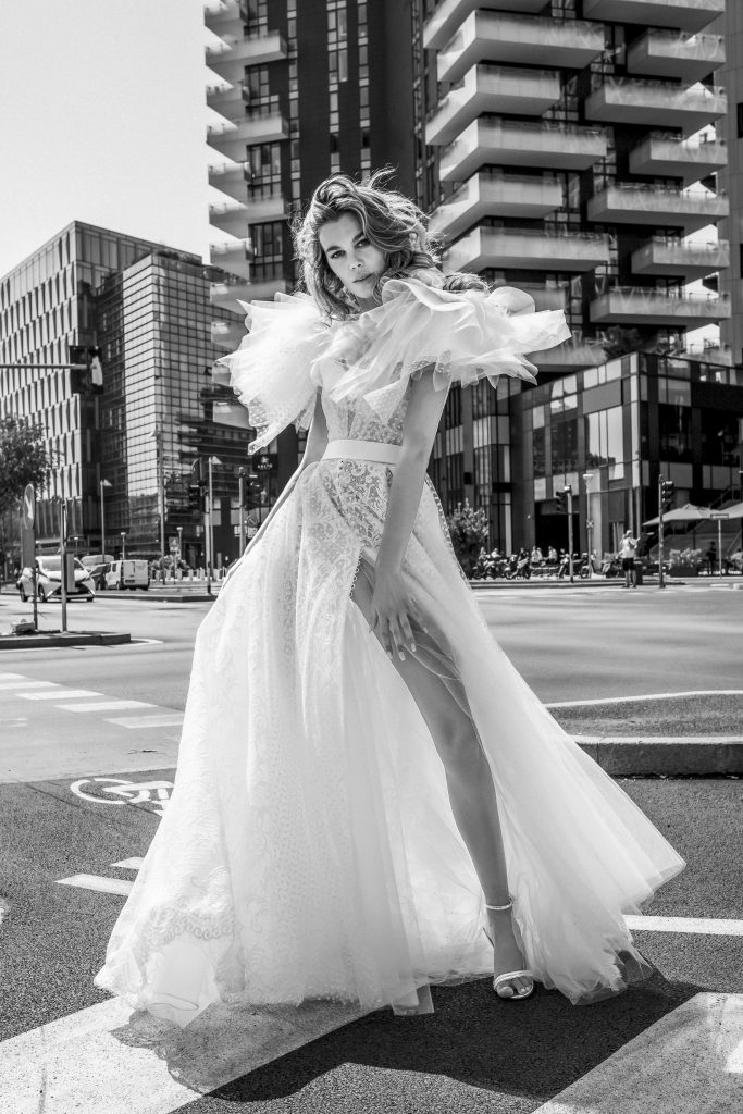 In questa immagine un abito da sposa Elisabetta Polignano 2023 con maniche in tulle e spacco profondo.