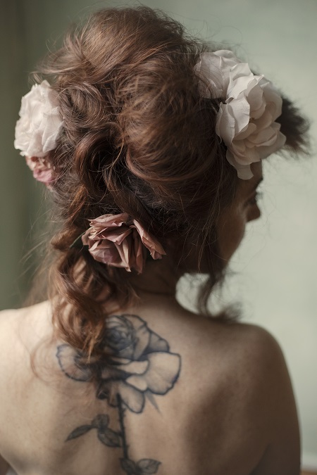 In questa foto, una sposa ripresa di spalle ha un'acconciatura strutturata con grandi rose 