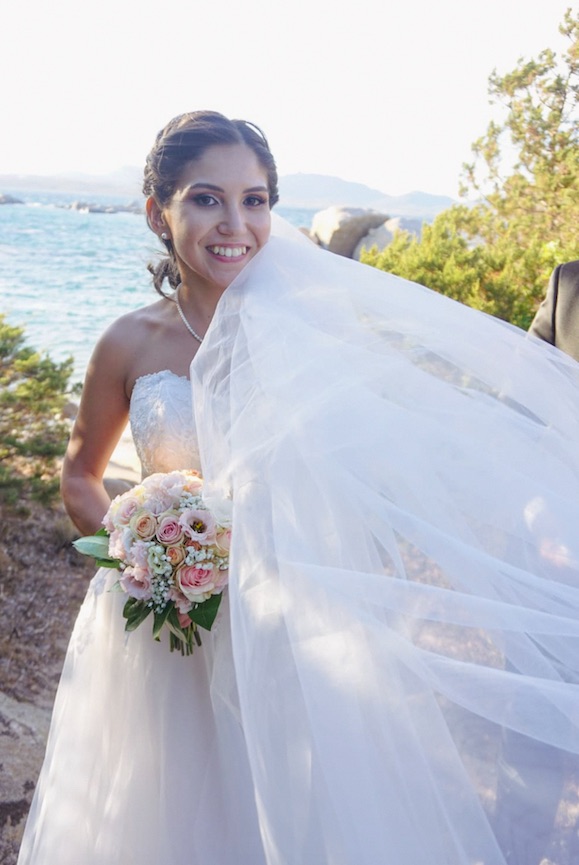 In questa foto la sposa Elena, mentre tiene tra le mani il bouquet con il mare sullo sfondo