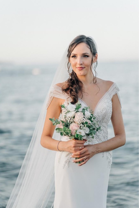 In questa foto la sposa Maria Laura posa con il mare alle spalle e il bouquet di rose rosa e bianche tra le mani