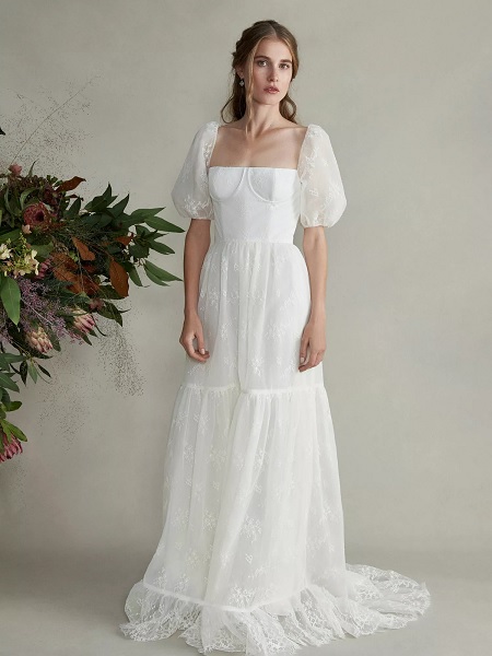 In questa foto, una sposa indossa un abito bianco con corpetto aderente, maniche a sbuffo e gonna morbida con disegni floreali di pizzo