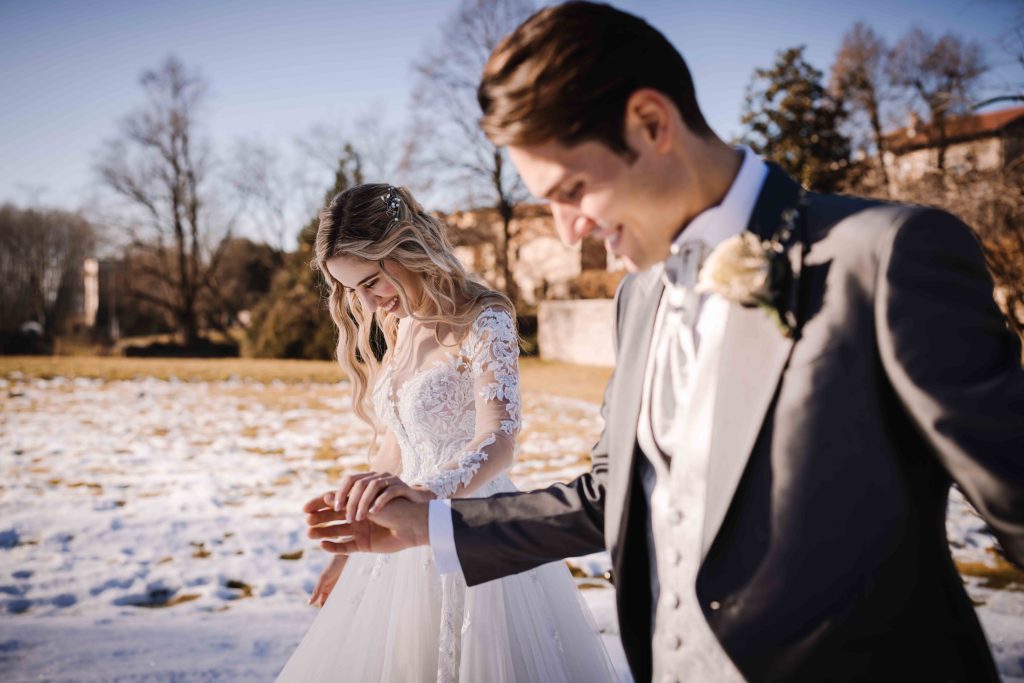 In questa foto una coppia di sposi in una località invernale: si tengono per mano camminando sulla neve