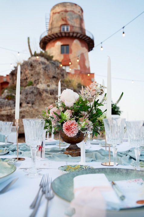 In questa foto il centrotavola domina sulla mise en place. Sullo sfondo il faro della Tonnara Florio di Palermo