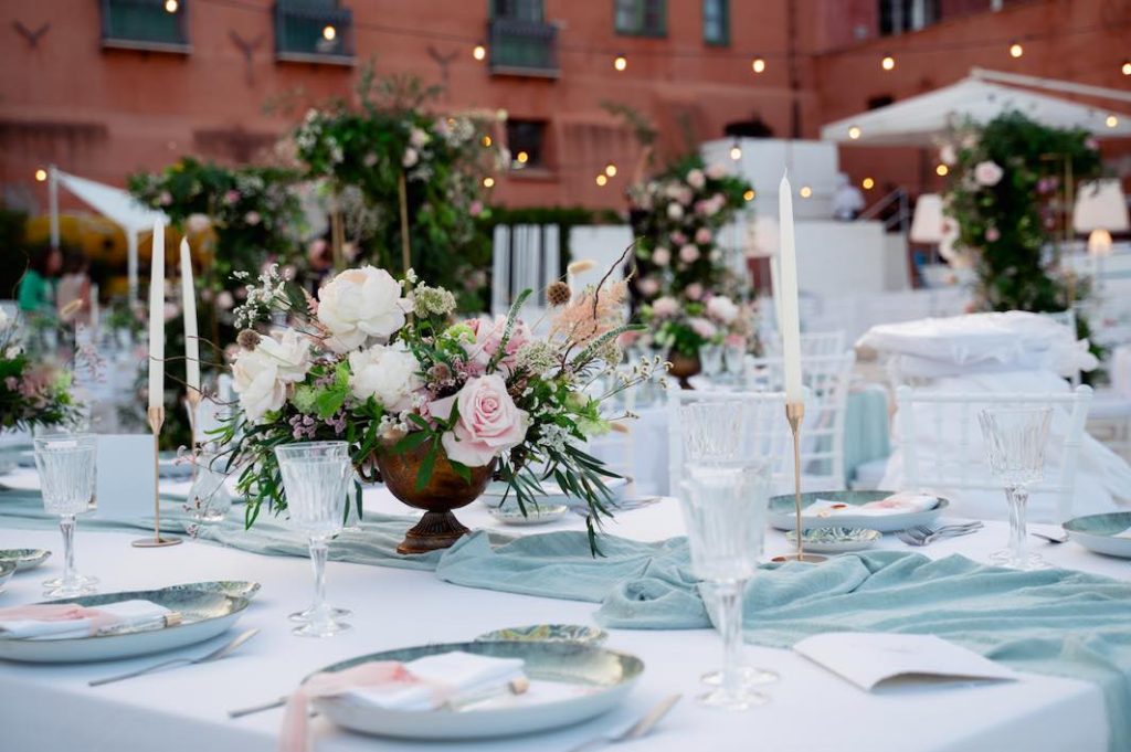 In questa foto, un dettaglio della mise en place realizzata per il matrimonio della direttrice di Sposi Magazine, Paola Pizzo: il centrotavola floreale, con rose, dalie, peonie e astilbe posizionati in piccole coppe, svetta su runner verde salvia. I piatti segnaposto sono verdi e al loro interno è posizionato il segnaposto con profumo personalizzato 