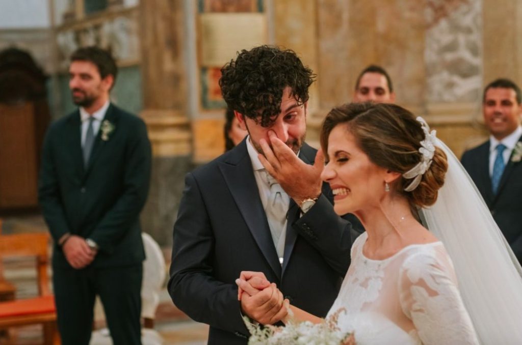 In questa foto Paola e Carlo appena arrivati all’altare, mentre lui si asciuga le lacrime di gioia e lei sfoggia un sorriso a 32 denti