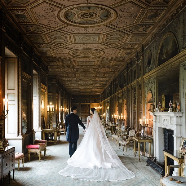 In questa foto, una coppia ritratta di spalle passeggia all'interno di un palazzo d'epoca, location ideale per un matrimonio stile Bridgerton 