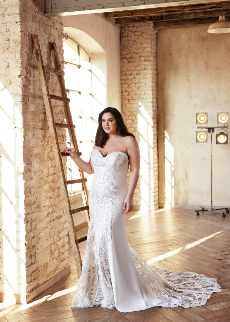 Un abito da sposa a sirena con ricami in pizzo e dettagli in trasparenza della nuova collezione curvy di Modeca. 