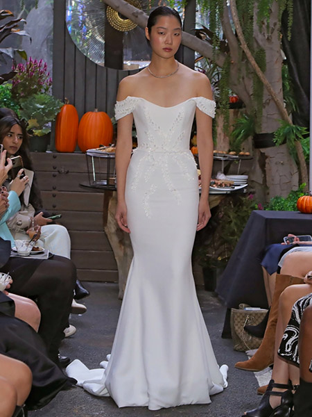 In questa foto la modella indossa un abito da sposa a sirena con bustino aderente e manica scivolata