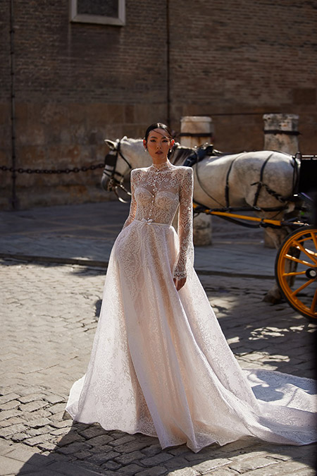 In questa foto la modella indossa un abito da sposa di pizzo a maniche lunghe Julie Vino