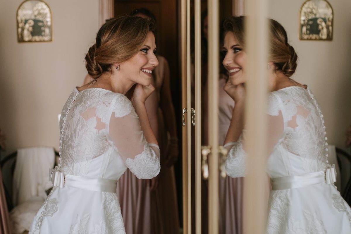 In questa foto Paola Pizzo, direttrice di Sposi Magazine, ritratta nel giorno del matrimonio mentre si guarda allo specchio e indossa degli orecchini