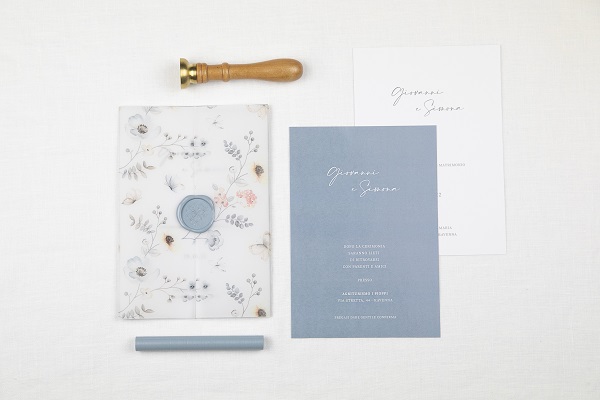 In questa foto, una partecipazione di nozze con biglietti interni in bianco e azzurro polvere e busta trasparente floreale chiusa con sigillo di ceralacca azzurro polvere 