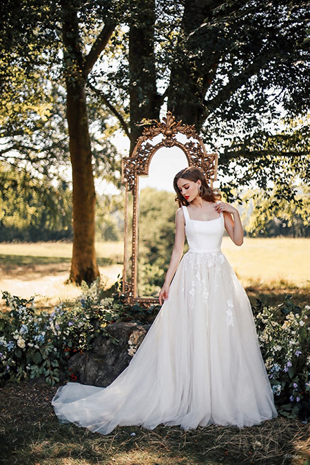 In questa foto la modella indossa un abito da sposa disney modello Snow White con scollo quadrato e gonna di tulle con fiori