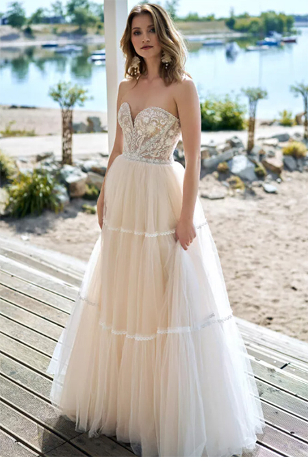 In questa foto la modella indossa un abito da sposa romantico 2023 con buistier con fiori e gonna di tulle 