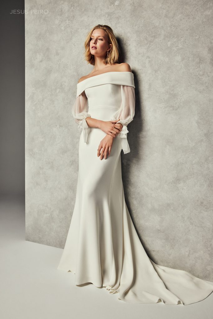 In questa foto la modella indossa un abito da sposa semplice 2023 con maniche trasparenti e scollo a barca
