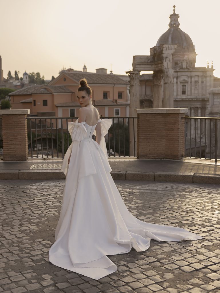 In questa foto un abito bianco in mikado di seta con spalle scoperte firmato Rara Avis