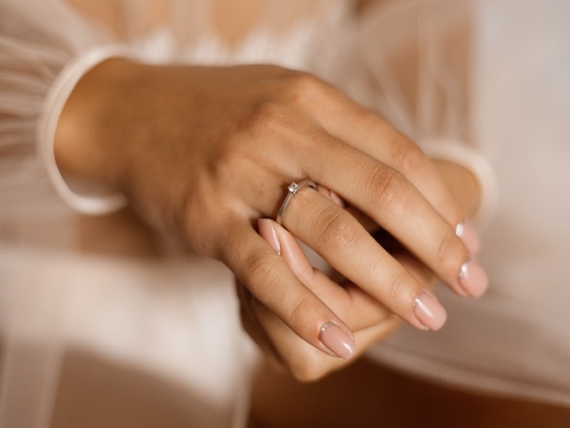 In questa foto le mani di una sposa che tiene tra le dita il suo anello di fidanzamento al suo anulare