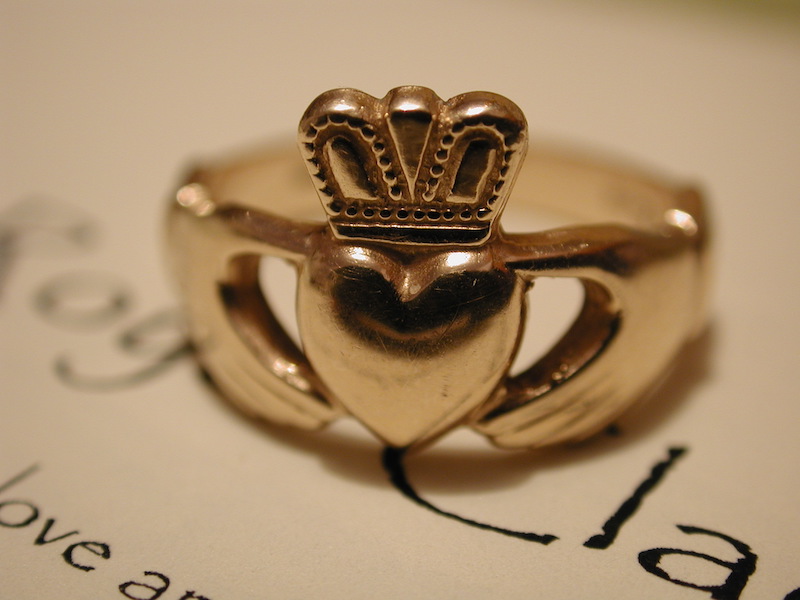 In questa foto un anello di fidanzamento irlandese in oro giallo con montatura formata da due mani che tengono un cuore al centro sormontato da una piccola corona