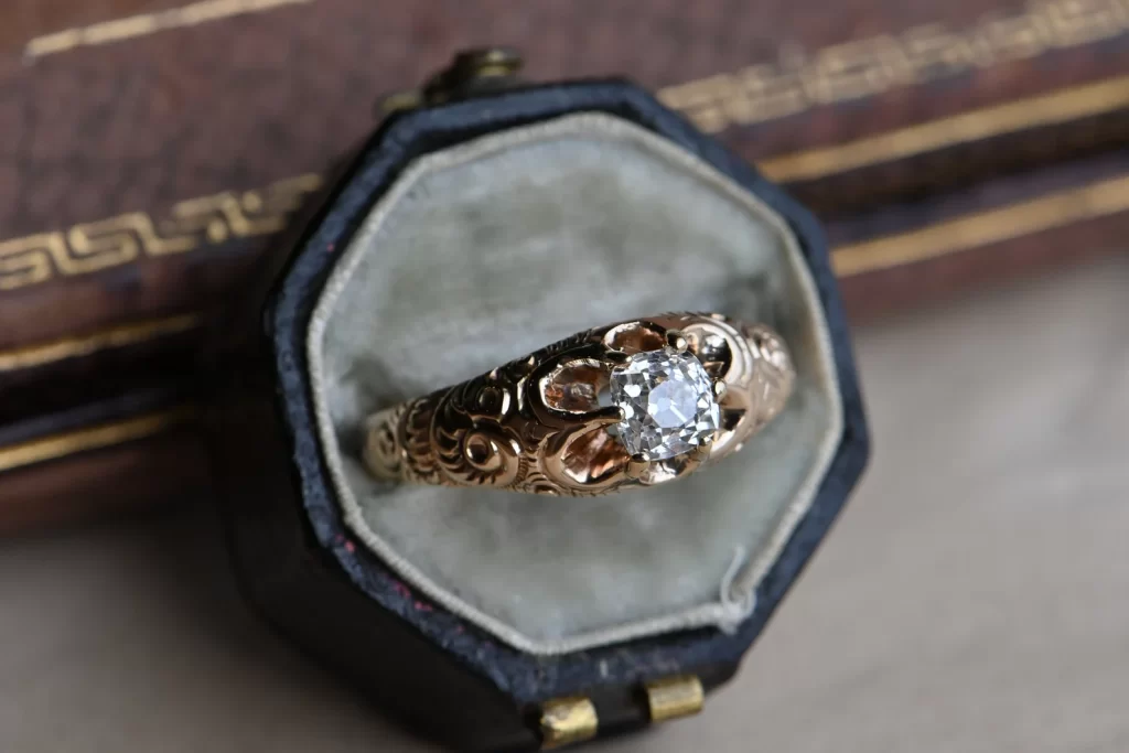 In questa foto un anello di fidanzamento vintage stile vittoriano in oro giallo con intarsi sulla montatura e diamante al centro