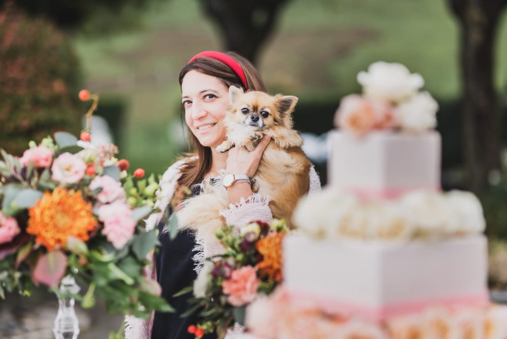 In questa foto la Wedding Coordinator Claudia Girola con il suo cane tra le braccia alle spalle di una Wedding Cake