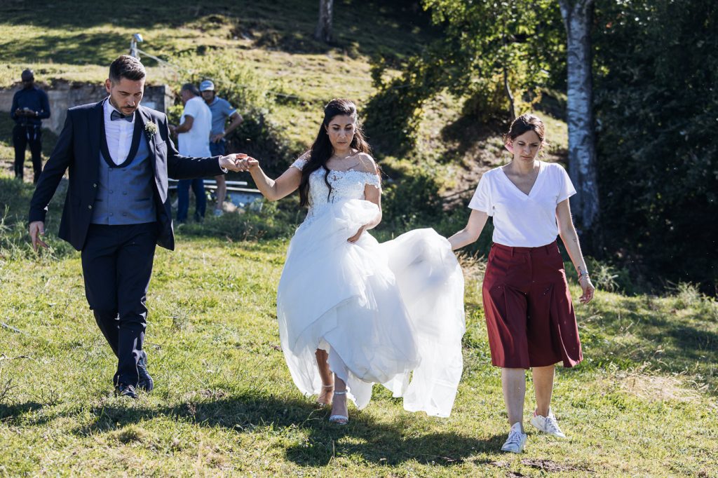 In questa foto Claudia Girola Wedding Coordinator tiene il velo alla sposa che cammina su un prato