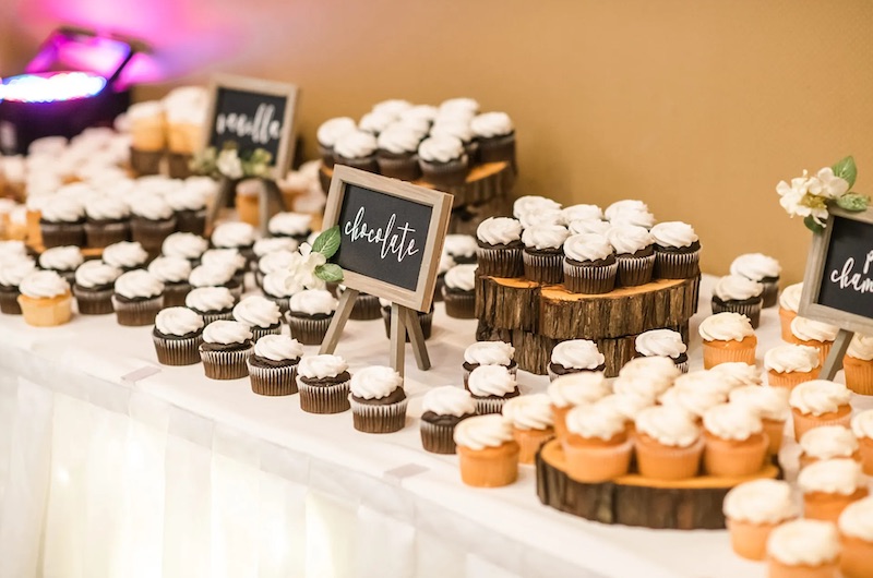 In questa foto uno sweet table con cupcake e piccole lavagne su cui è scrutto il gusto 