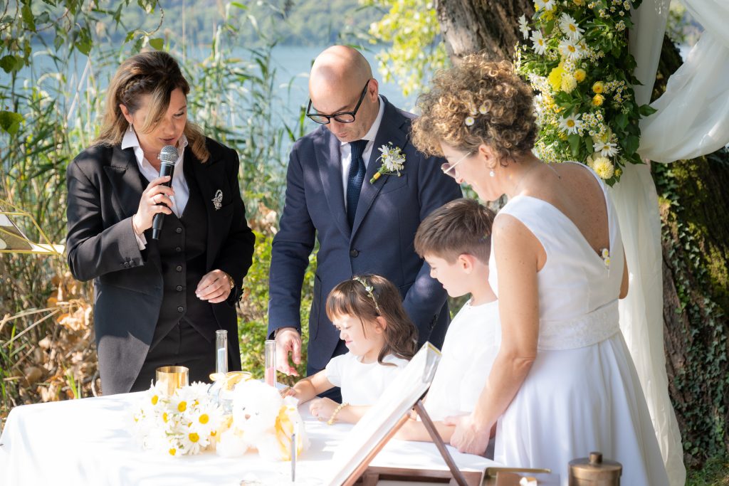 In questa foto una coppia di sposi insieme ai figli firma l'atto di matrimonio in un rito di Gabriella Maran Celebrante