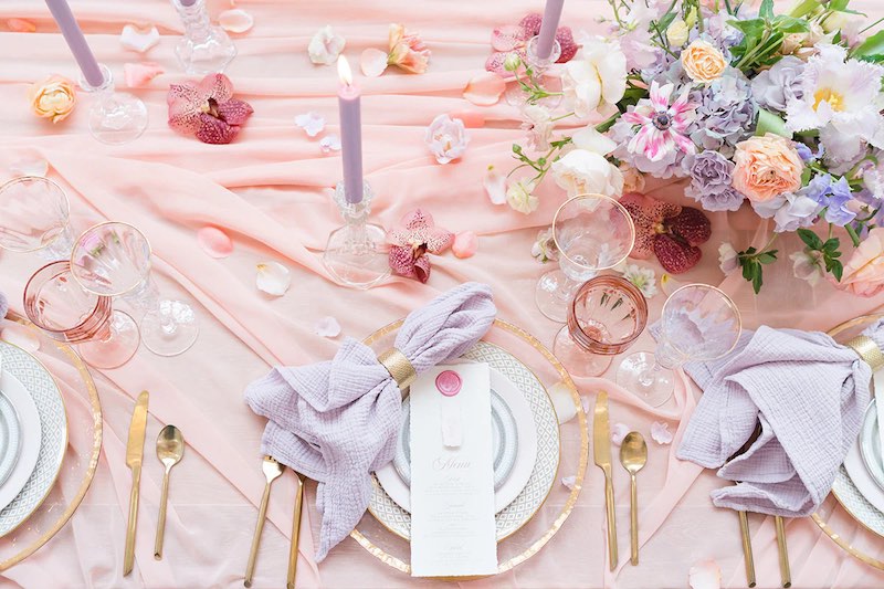 In questa foto una mise en place per matrimonio stile Bridgerton nei torni del rosa, del lilla e dell'oro 