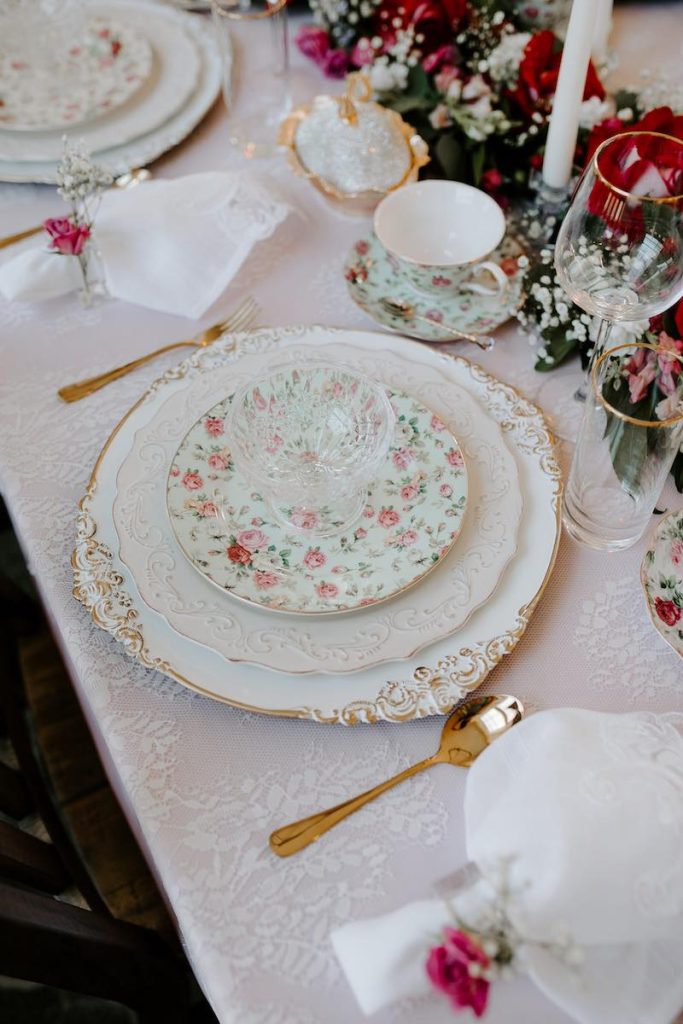 In questa foto una mise en place per matrimonio in stile Bridgerton con porcellane decorate con fiori di colore rosa