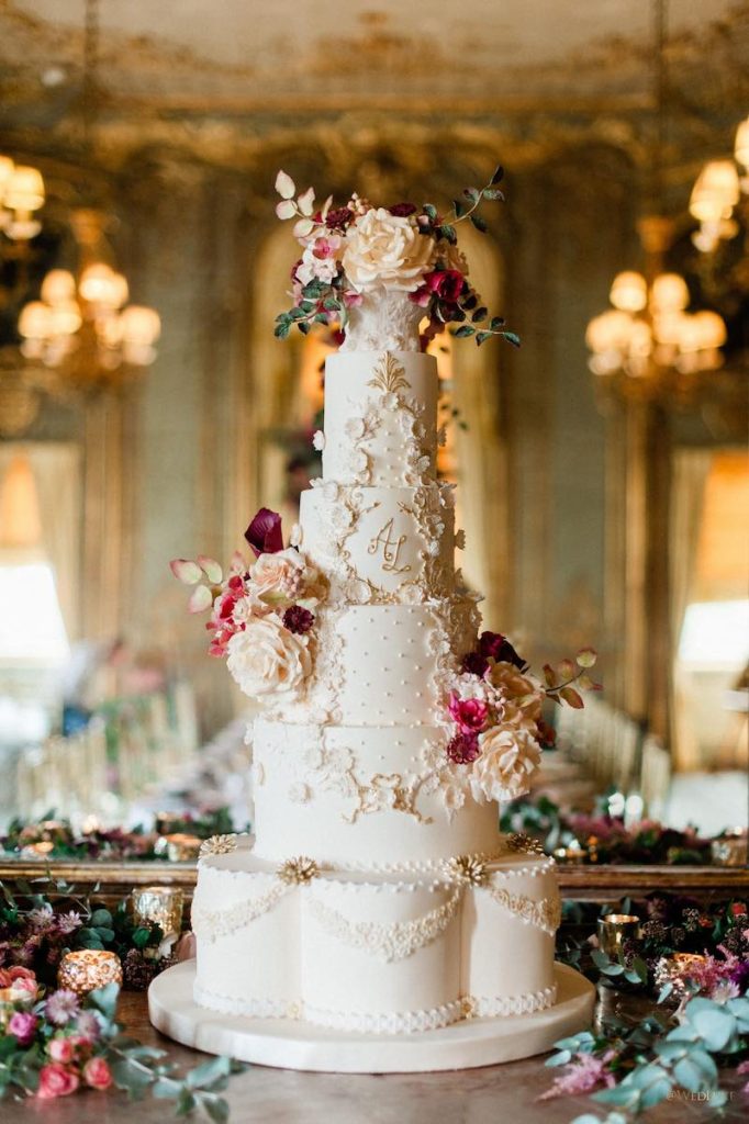 In questa foto una torta per matrimonio barocco a piani di colore bianco decorata con fiori
