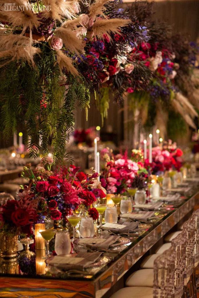 In questa foto un tavolo per matrimonio imperiale allestito in stile barocco con fiori di colore fucsia e rosa, pampas e cristalli