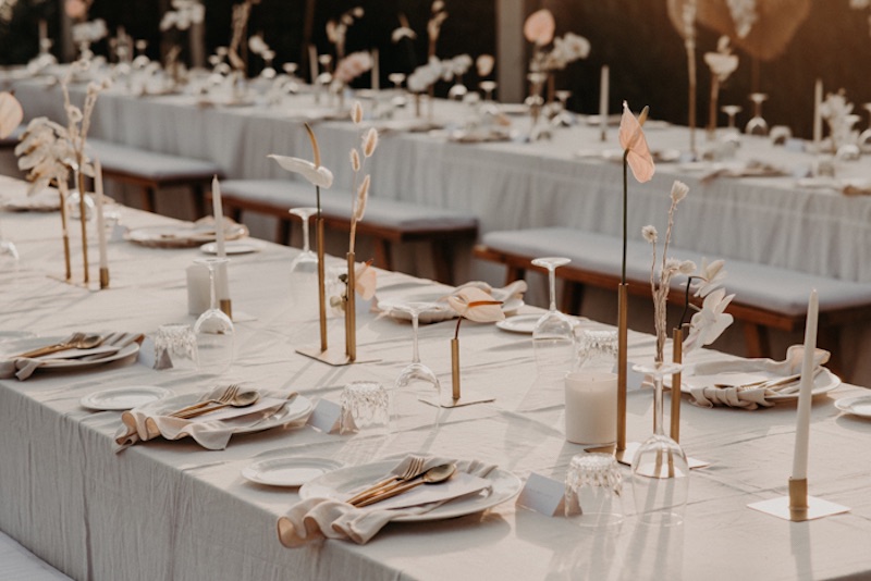 In questa foto un tavolo per matrimonio allestito in stile minimal con fiori di colore bianco, vasetti e tovaglioli abbinati