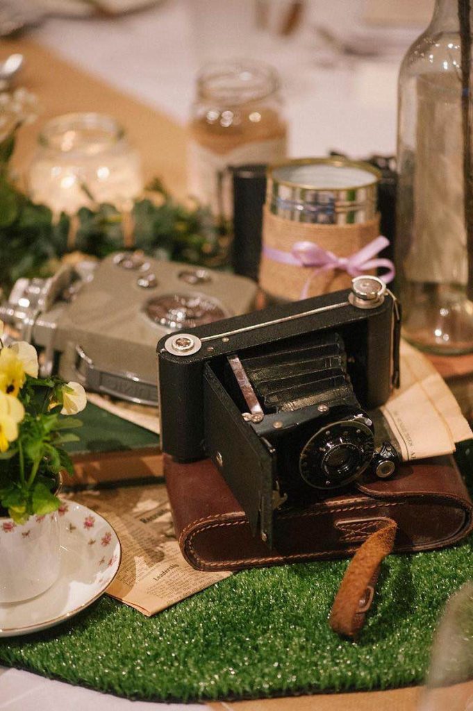 In questa foto un centrotavola per matrimonio in stile vintage realizzato con una antiche macchine fotografiche