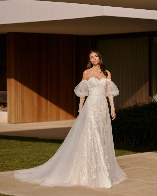 In questa foto una modella indossa un abito da sposa trasformabile 2023: fa parte della linea Rosa Clarà e ha sopragonna e maniche removibili