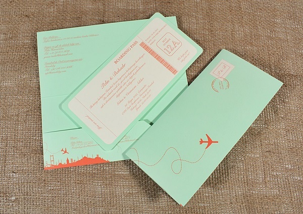 In questa foto, un invito matrimonio fai da te tema viaggio a forma di biglietto aereo sui toni del beige, del verde menta e dell'arancio 