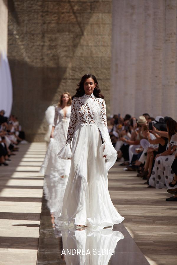 In questa foto la modella indossa un abito da sposa scivolato con maniche lunghe di pizzo Andrea Sedici