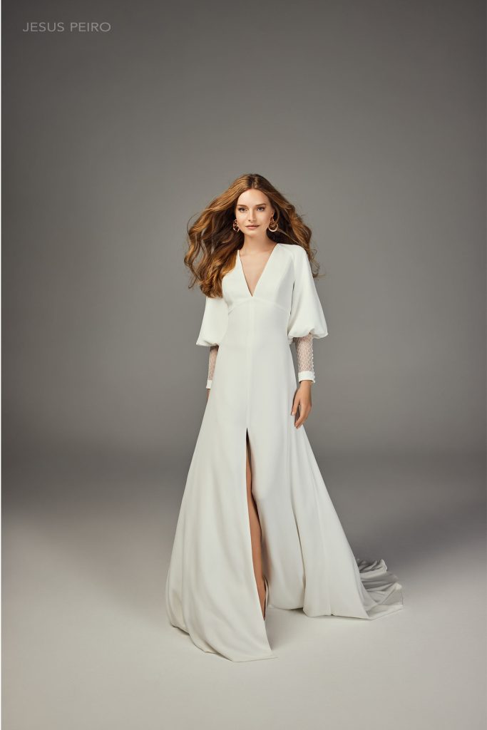 In questa foto la modella indossa un abito da sposa scivolato con scollo a V maniche lunghe e spacco Jesus Peiro