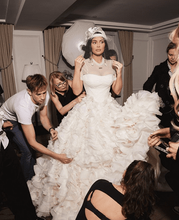 In questa foto Kylie Jenner al Met Gala con un abito da sposa mentre il suo staff la aiuta ad indossarlo