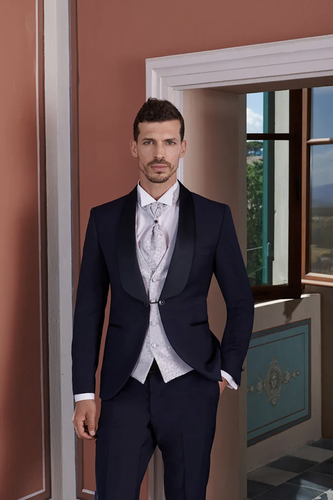 In questa immagine un abito da sposo di Rocchini Cerimonia con gilet e cravatta a contrasto.