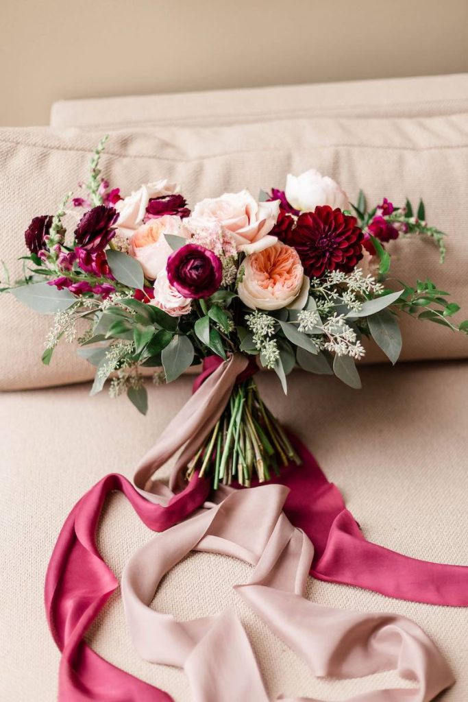 In questa foto un bouquet da sposa con fiori nel colore matrimonio 2023 Viva Magenta abbinati a fiori e a nastri di colore rosa