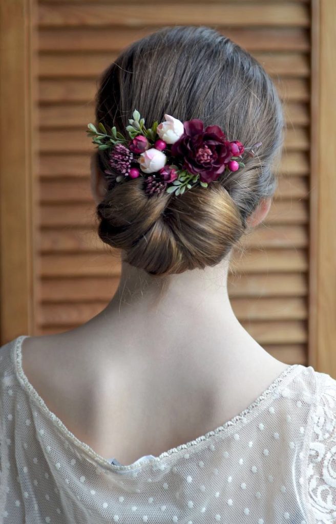 In questa foto un fermaglio da sposa con fiori nel colore matrimonio 2023 Viva Magenta abbinati a boccioli di colore rosa
